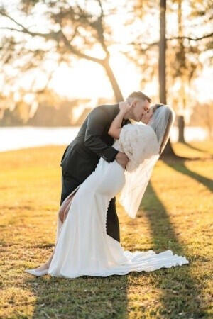 South Carolina Wedding Photographer - Stories and Stills from the mountains to the coast. A newly married couple embraces in the glow of the sunset at golden hour surrounded by oak trees covered in Spanish moss near a shimmering lake. Get the best wedding photographers in South Carolina.